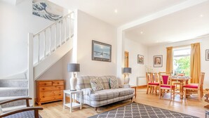 A spacious living room with a staircase, a dining area, and a view of the outdoors.