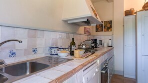 A kitchen with a sink, stove, and various appliances. There are tiles on the wall and a window above the stove. - Casale dei Tigli 8, Emma Villas (Castel Giorgio)