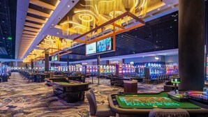 Een casino met meerdere gokkasten, een roulette tafel en een kassa.