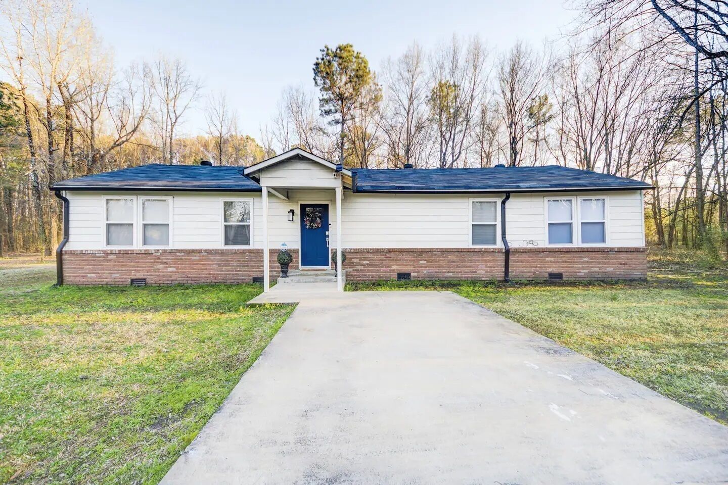 A two-story house with a front porch, a blue door, and a brick foundation.