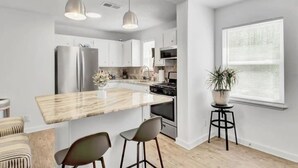 Een moderne keuken met een centraal eiland, roestvrijstalen apparatuur en hanglampen.