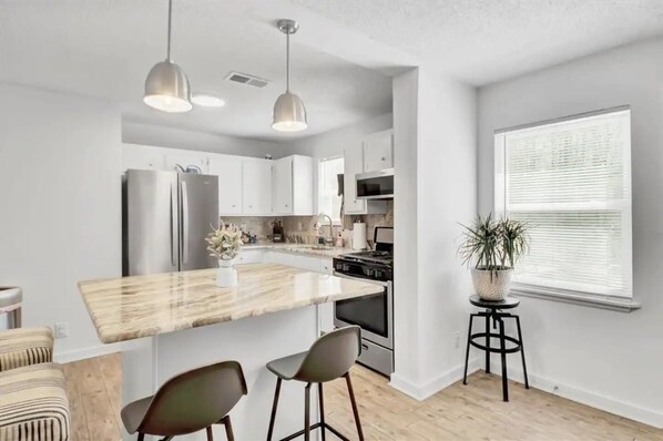 A modern kitchen with a central island, stainless steel appliances, and pendant lighting.