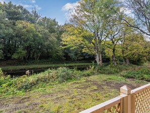 A riverside park with a wooden deck and dense trees.