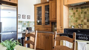 Eine Küche mit Holzausstattung, einem Bosch-Kühlschrank, einem Herd und einem Esstisch mit Stühlen.