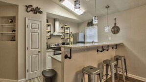 A compact kitchen with a central island, bar stools, and pendant lighting. - Large Groups Welcome (Go Seminoles, Go Rattlers) (Tallahassee)