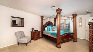 A bedroom with a four-poster bed, a chair, a nightstand, and a mirror on the wall. - Beautiful 2 Story Near Seaworld and Lackland AFB (San Antonio)