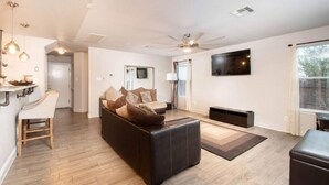 A modern living room with a sofa, a TV, a ceiling fan, and a window. - Beautiful 2 Story Near Seaworld and Lackland AFB (San Antonio)