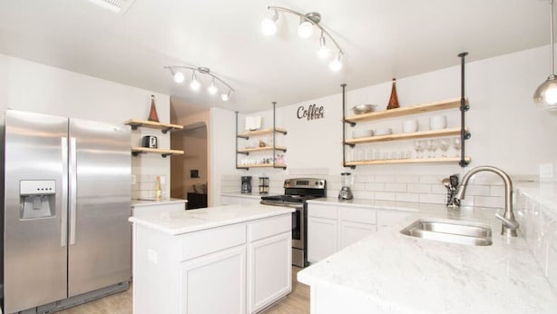 A modern kitchen with a central island, stainless steel appliances, and open shelving. - Beautiful 2 Story Near Seaworld and Lackland AFB (San Antonio)