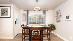 A dining area with a wooden table, chairs, a pendant light, and a window with curtains. - Beautiful 2 Story Near Seaworld and Lackland AFB (San Antonio)