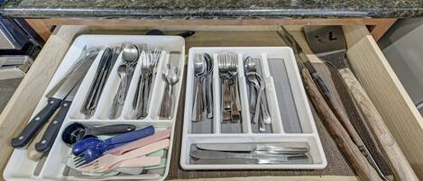 A drawer with neatly organized utensils including knives, forks, spoons, and a pair of scissors.