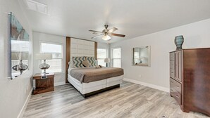 Un dormitorio con cama, ventilador de techo, cómoda y espejo.