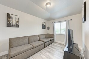 Un salon comprenant un canapé d’angle, un téléviseur à écran plat et deux tableaux encadrés accrochés au mur.