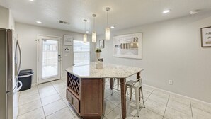 Una cocina moderna con una isla de mármol, iluminación colgante y vistas a la ciudad.