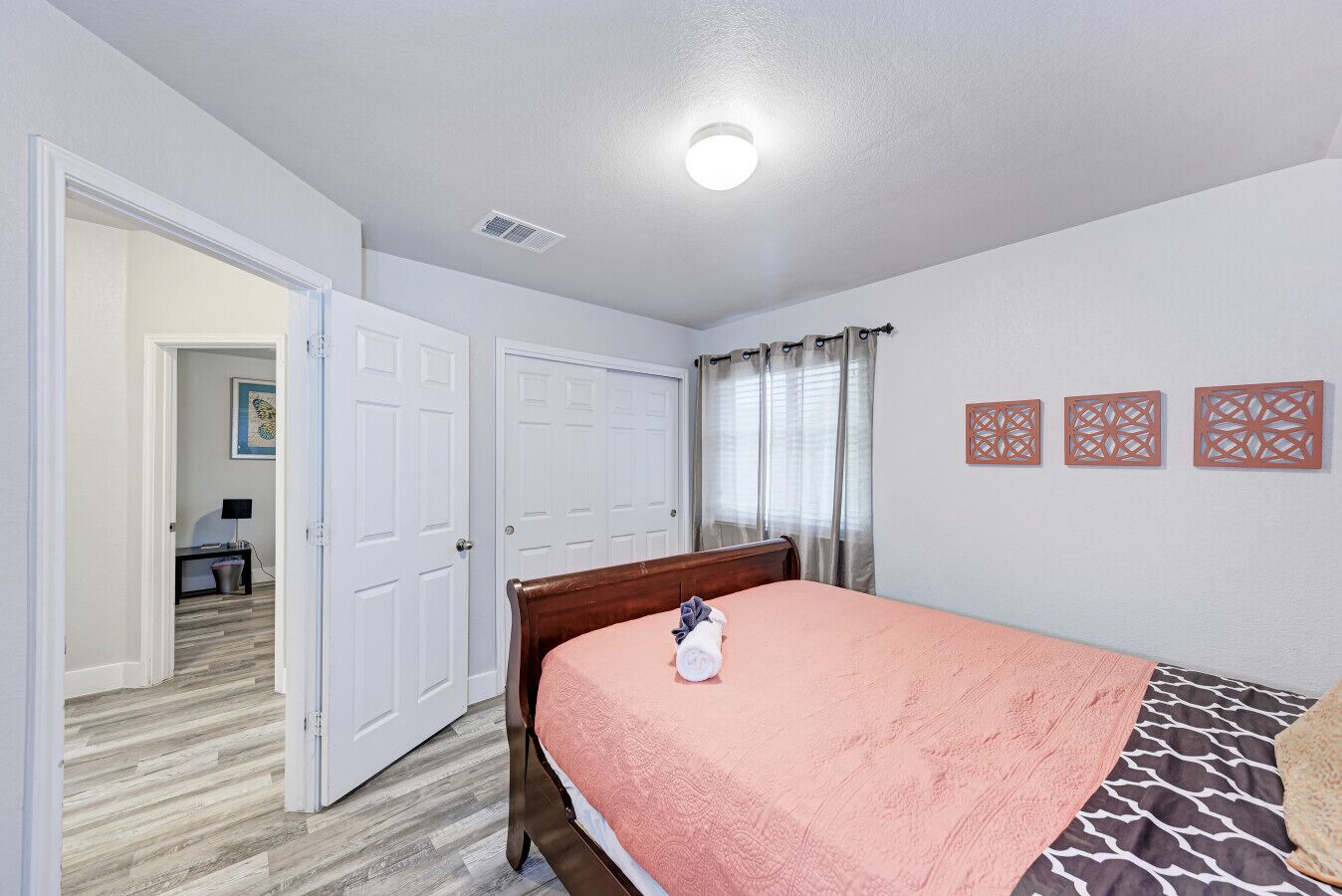 Un dormitorio con cama, una puerta, un ventanal con cortinas y una pared con paneles decorativos.
