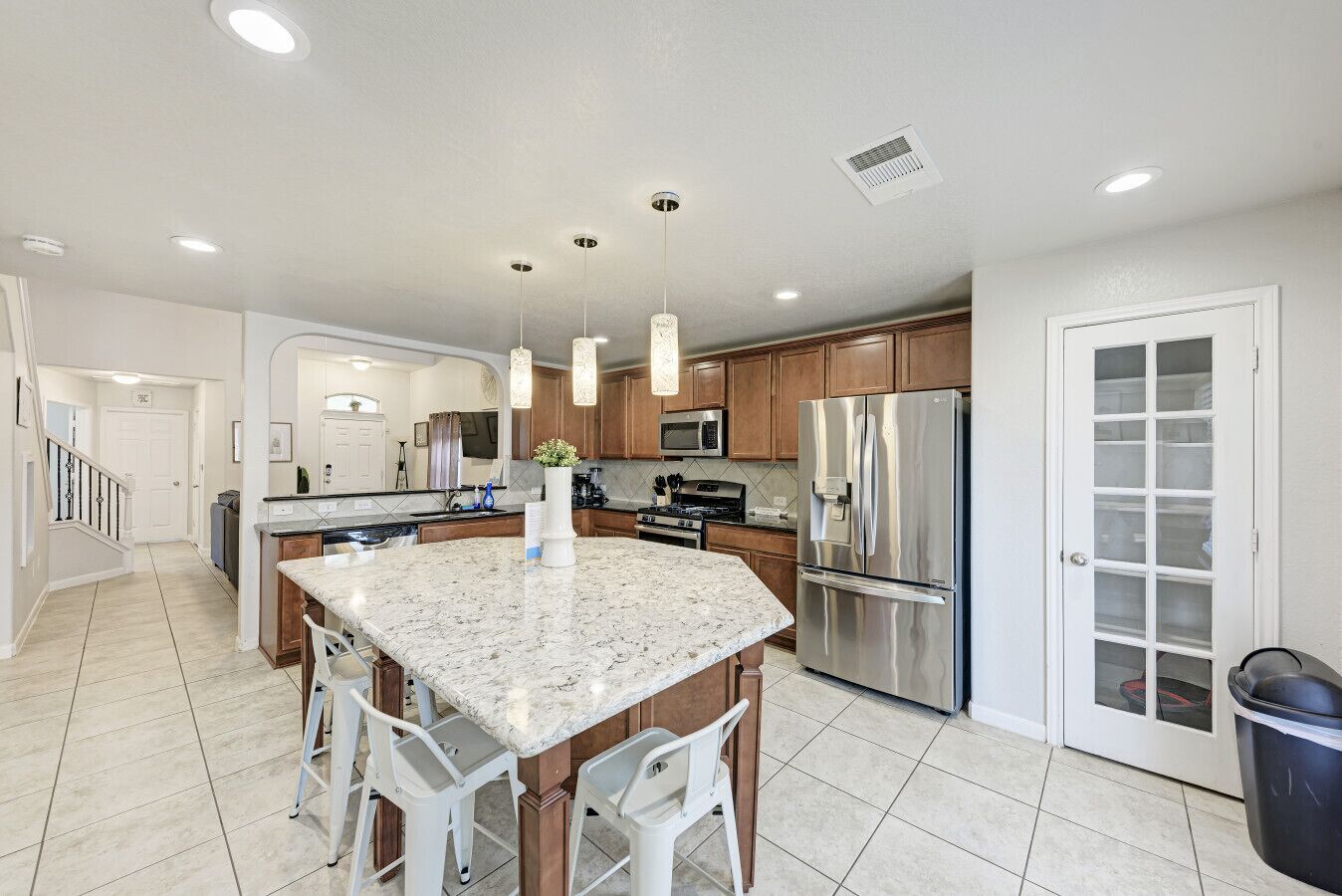 A modern kitchen with granite countertops, stainless steel appliances, and pendant lighting.