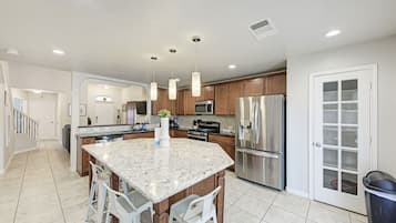 A modern kitchen with granite countertops, stainless steel appliances, and pendant lighting.