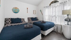A bedroom with two beds, a window with curtains, a wall clock, and a small table with a lamp. - Newly Renovated Home near Kalahari Resorts (Round Rock)