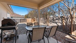 An outdoor patio with a table and chairs, a grill, and a covered area. - Newly Renovated Home near Kalahari Resorts (Round Rock)