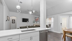 A modern kitchen with white cabinetry, a dishwasher, a sink, and a ceiling fan. - Newly Renovated Home near Kalahari Resorts (Round Rock)