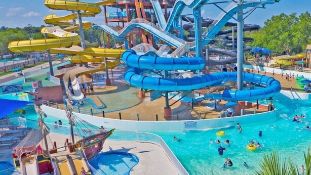 Un parque acuático con múltiples toboganes, una zona de piscina y una estructura con temática náutica.