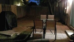 Une terrasse extérieure avec une table et des chaises, un barbecue et un espace salon abrité.
