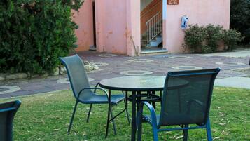 A patio area with outdoor seating, a staircase leading to an entrance, and a building with a pink facade.