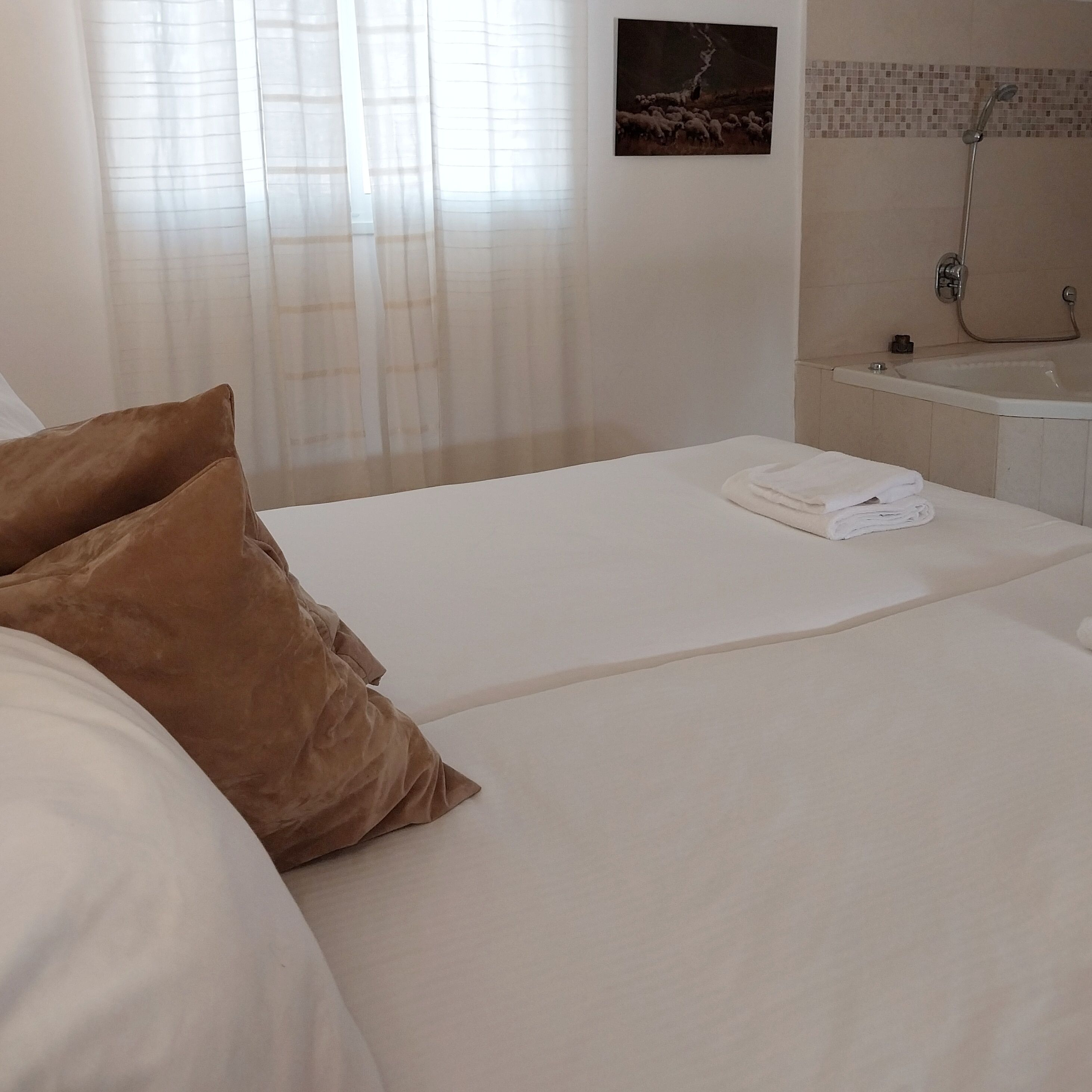 Une chambre d’hôtel avec un lit, une salle de bain avec douche et un tableau au mur.