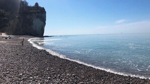 A pebbled beach with a large cliff and calm sea. - Seaside villa in Normandy, exceptional setting (Saint-Pierre-en-Port)
