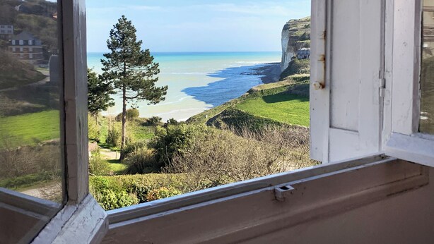 A coastal view from a window overlooking a beach, grassy areas, and a cliff. - Seaside villa in Normandy, exceptional setting (Saint-Pierre-en-Port)