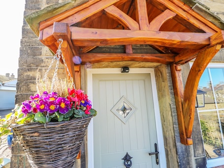 A wooden porch with a hanging basket of flowers.