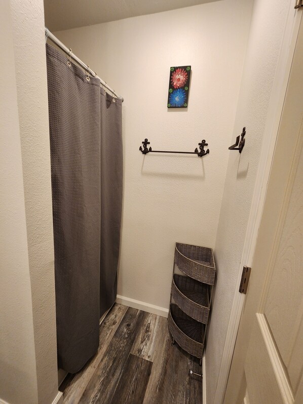 A bathroom with a shower curtain, a towel rack, and a wicker basket.