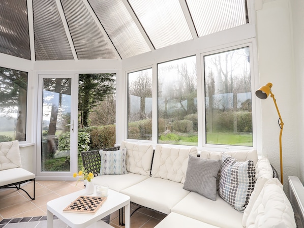 A conservatory with a white sofa, a chessboard, and a lamp.