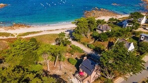 Oversigtsbillede af en ejendom ved kysten med en strand, klippefyldt kystlinje og frodig vegetation.