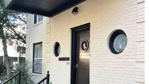 A modern house with a black door, two round windows, and a large golden anchor decoration on the front porch. - Lower Greenville Studio (Dallas)