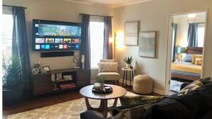 A living room with a flat-screen TV, a sofa, a coffee table, and a ceiling fan. - Lower Greenville Studio (Dallas)