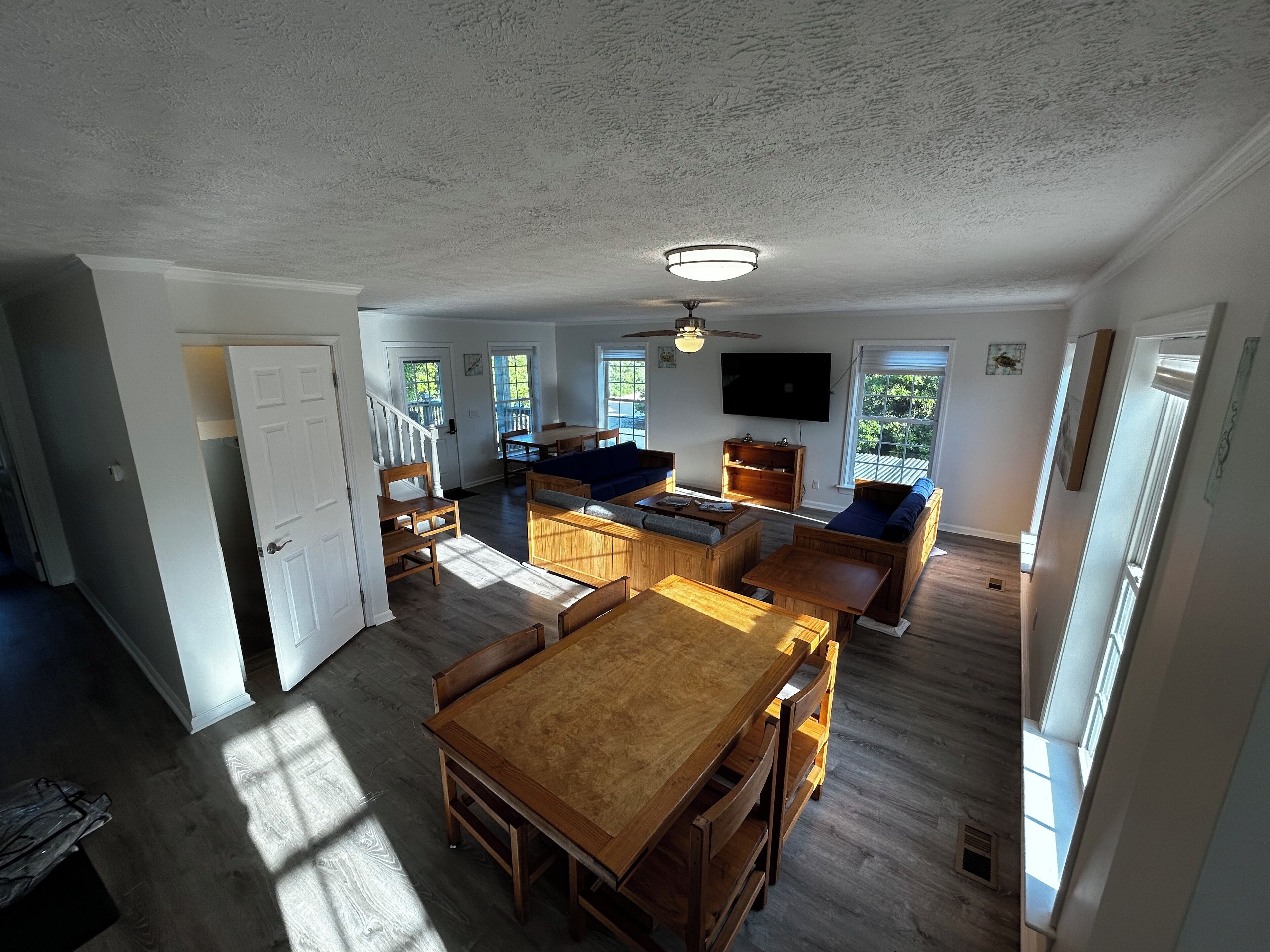 Un'ampia zona giorno con un tavolo da pranzo in legno, sedute integrate e una ventola a soffitto.