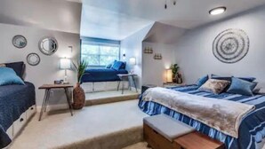 Un dormitorio con dos camas, una mesita, un banco y una ventana.