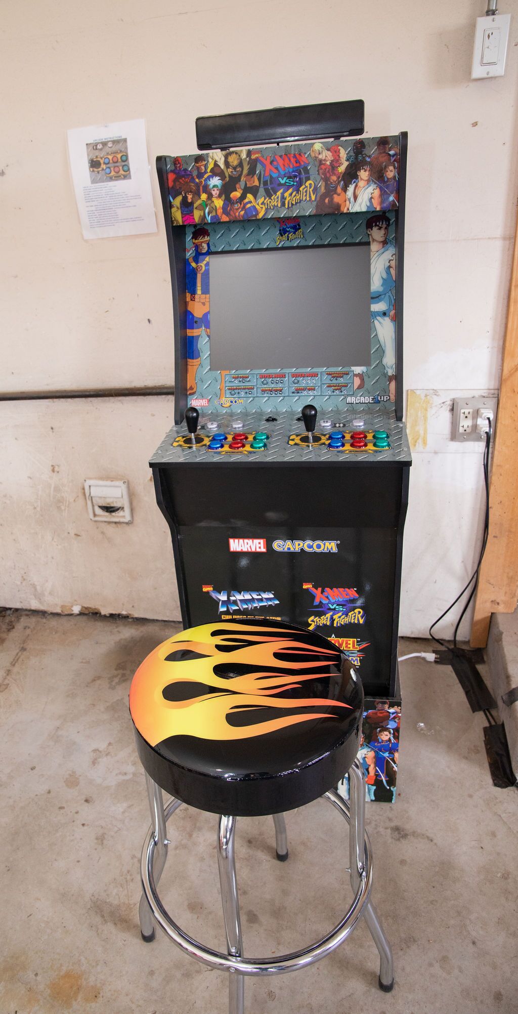 A vintage arcade machine with a joystick and button panel, featuring X-Men vs. Street Fighter graphics.