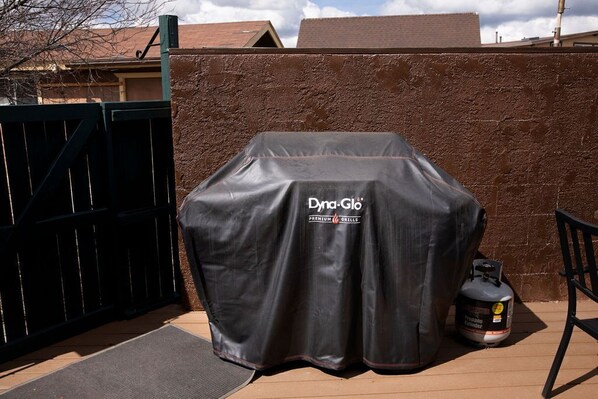 A covered grill with a Dynagló Premium Grill label, a propane tank, and a black gate. - family getaway with hot tub and game room on 2 acres (Flagstaff)