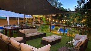 Eine Außenpatio-Terrasse mit Korbmöbeln, einem Pool und Lichterketten.