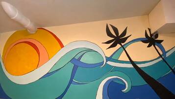 Una pintura abstracta y colorida que muestra un sol, olas y dos flores negras.