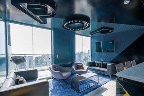 Una sala de estar moderna con un ventanal grande, un sofá, dos sillones, una mesa de centro y una mesa de comedor.