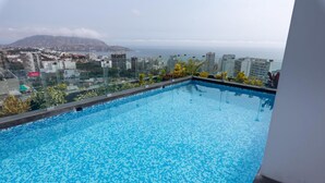 A rooftop pool with a city view, surrounded by plants and a clear sky. - Modern 1Bd Apt in the Best of Barranco Miraflores (Lima)