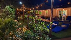 An outdoor area with string lights, a wooden pergola, and lounge chairs. - Surfer Shack 2 King Bedrooms (1 is a Loft) (East End)