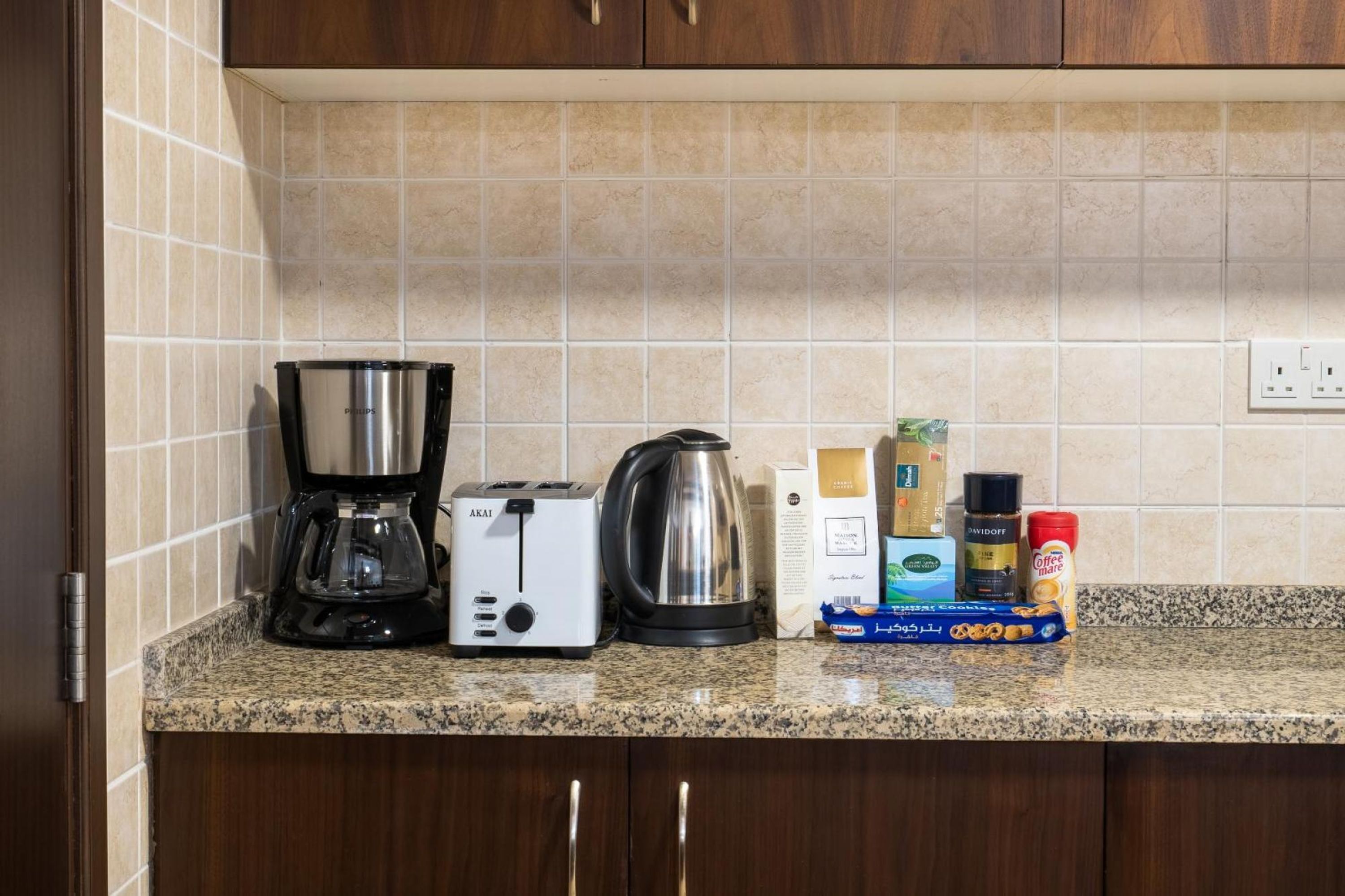 A kitchen counter with a coffee maker, toaster, kettle, and various coffee products.