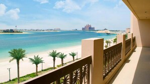 Un balcon donnant sur une plage et un bâtiment situé au loin.