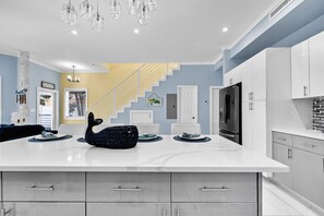 Enjoy cooking in this kitchen with a large island and ample workspace, complemented by white cabinetry and a stainless steel refrigerator.