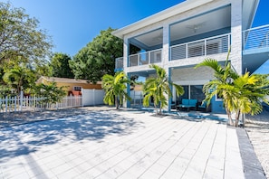 Uma casa moderna de dois andares com varanda, área de piscina e cerca branca de piquete.