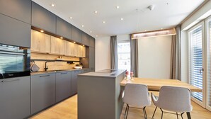 Uma cozinha moderna com armários cinza, bancada de madeira e uma ilha central com duas cadeiras cinzas.
