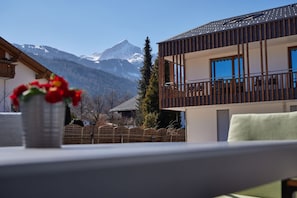 A modern building with a balcony, a mountain view, and a wooden fence in the foreground. - Murmeli - cosy ground floor flat in a central location (Garmisch-Partenkirchen)